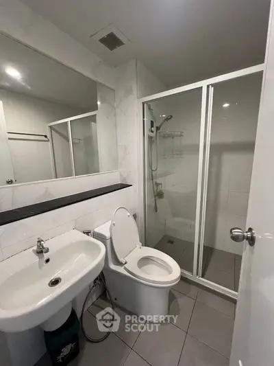 Modern bathroom with sleek fixtures and glass shower enclosure in contemporary apartment.