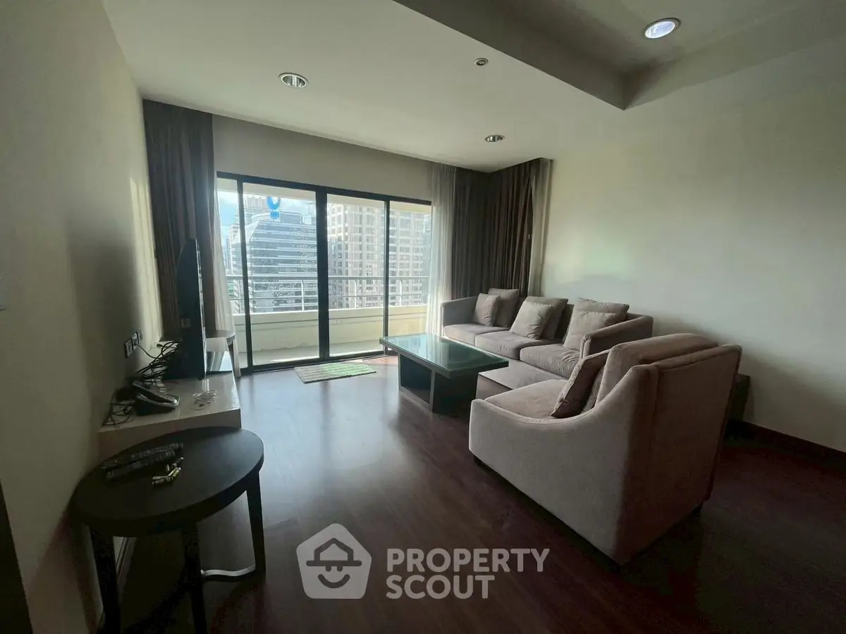 Spacious living room with modern furniture and city view balcony.
