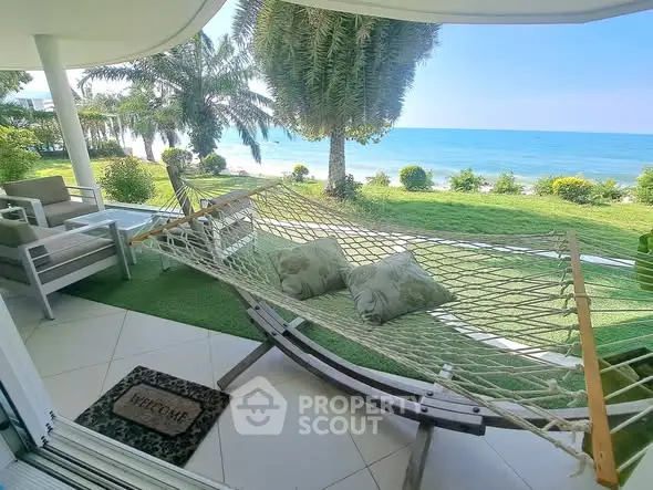 Stunning beachfront view from a luxurious patio with hammock and seating area.