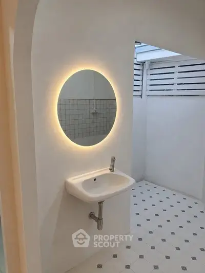 Modern bathroom with illuminated round mirror and sleek sink design