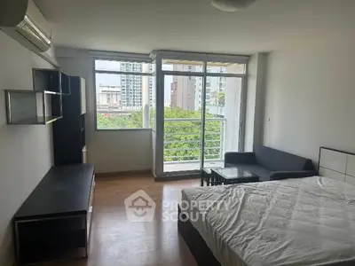 Spacious studio apartment with large windows and balcony view in modern urban setting.
