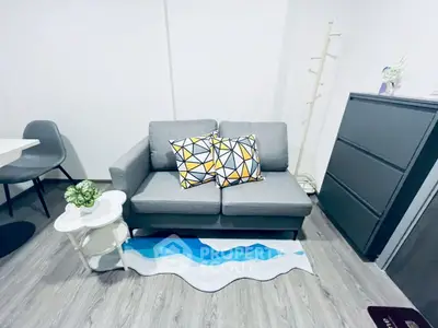 Modern living room with stylish gray sofa and geometric cushions, complemented by chic decor and sleek flooring.