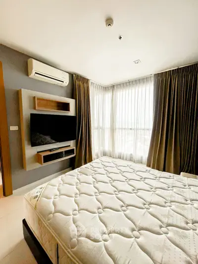 Modern bedroom with large windows and wall-mounted TV in a stylish apartment.