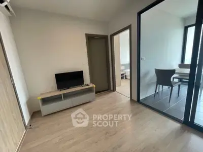 Modern apartment interior with sleek wooden flooring and glass-enclosed dining area.