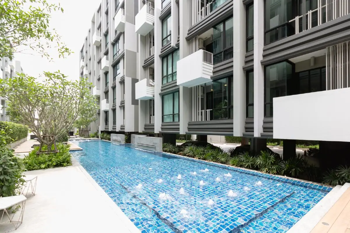 Modern apartment building with a luxurious swimming pool and lush greenery.