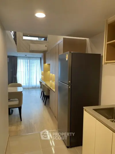 Modern apartment interior with open kitchen and dining area, featuring sleek cabinetry and natural light.