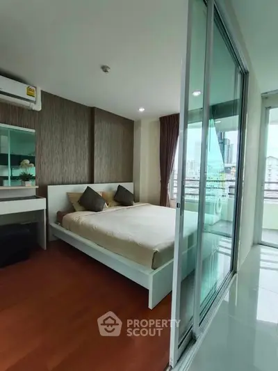 Modern bedroom with large windows and city view, featuring stylish decor and wooden flooring.
