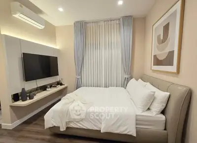 Modern bedroom with stylish decor, featuring a cozy bed, wall-mounted TV, and elegant curtains.