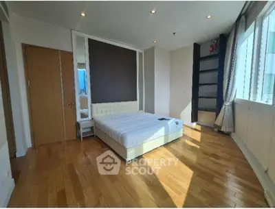Spacious bedroom with wooden flooring and large windows for natural light.