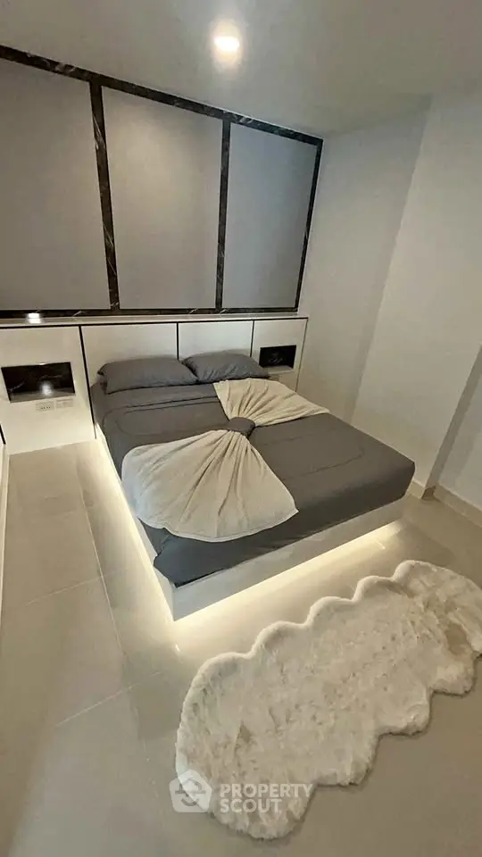 Modern bedroom with sleek design and ambient lighting, featuring a cozy bed and plush rug.