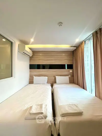 Modern bedroom with twin beds and large window for natural light