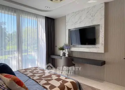Luxurious bedroom with large window and modern decor, featuring a wall-mounted TV and elegant furnishings.