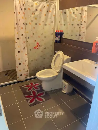 Modern bathroom with shower, toilet, and stylish sink in a cozy apartment.
