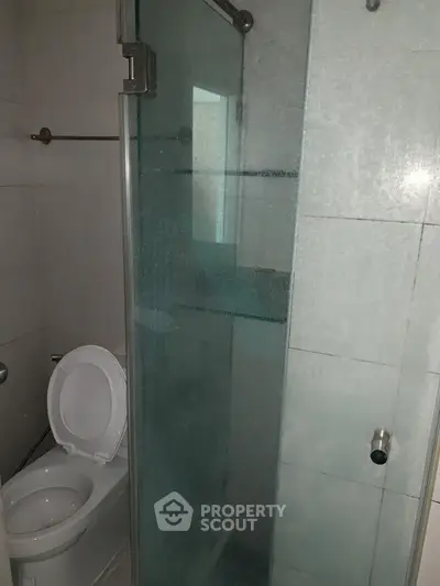 Compact bathroom with glass shower enclosure and toilet, ideal for modern apartments.