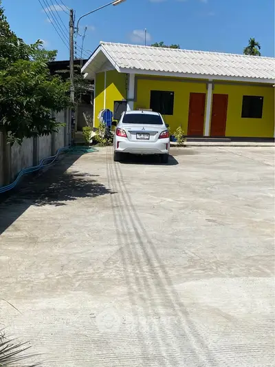 Spacious parking area in front of a vibrant yellow building with a white car parked.