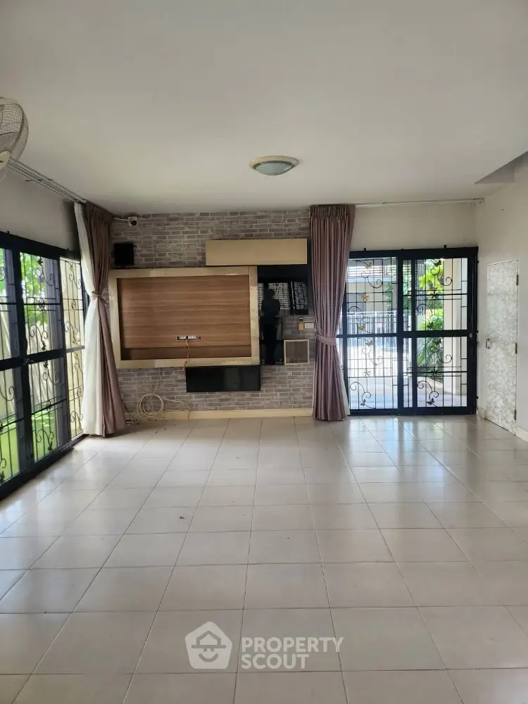 Spacious living room with large windows and tiled flooring