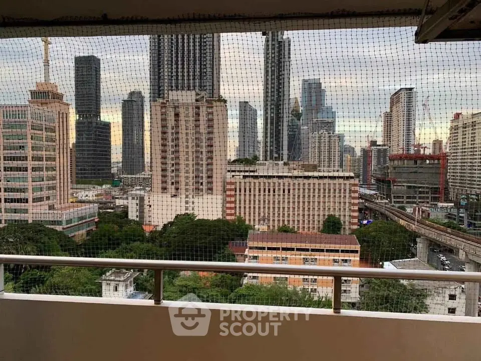 Stunning cityscape view from a high-rise balcony overlooking urban skyline and lush greenery.