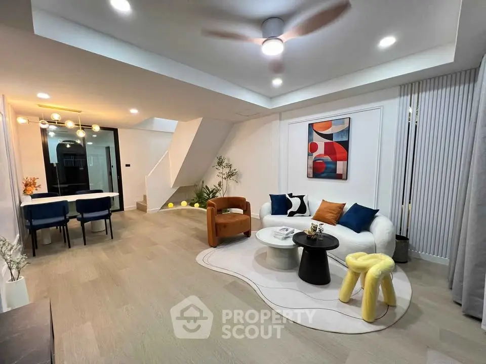 Modern living room with stylish furniture and open dining area, featuring contemporary art and lighting.