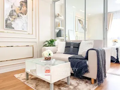 Elegant living room with modern decor and cozy seating area, featuring stylish artwork and natural light.