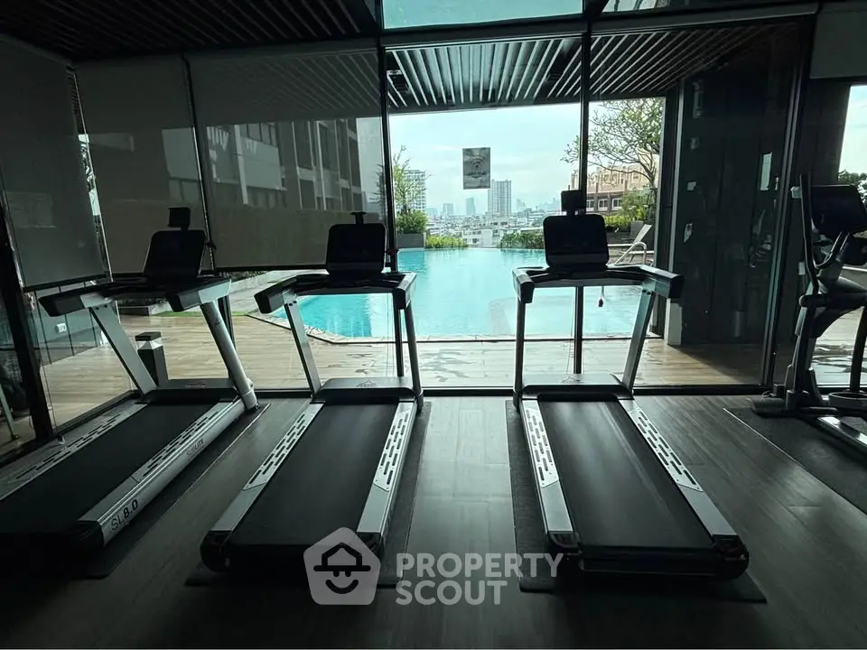 Modern gym with treadmills overlooking a stunning pool view in luxury real estate setting.