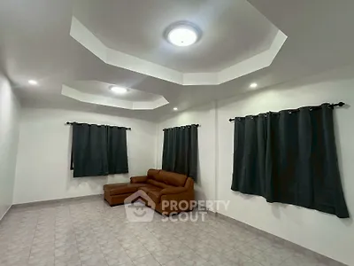 Spacious living room with modern ceiling design and cozy brown sofa, perfect for relaxation.