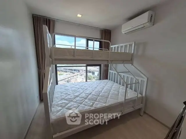 Modern bedroom with bunk bed and large window offering city view.