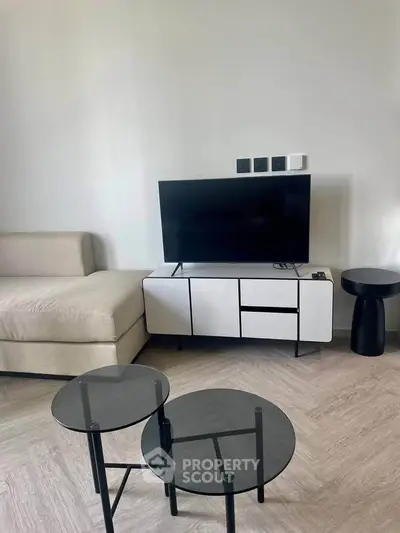 Modern living room with sleek TV stand, stylish coffee tables, and cozy sofa in a chic apartment.