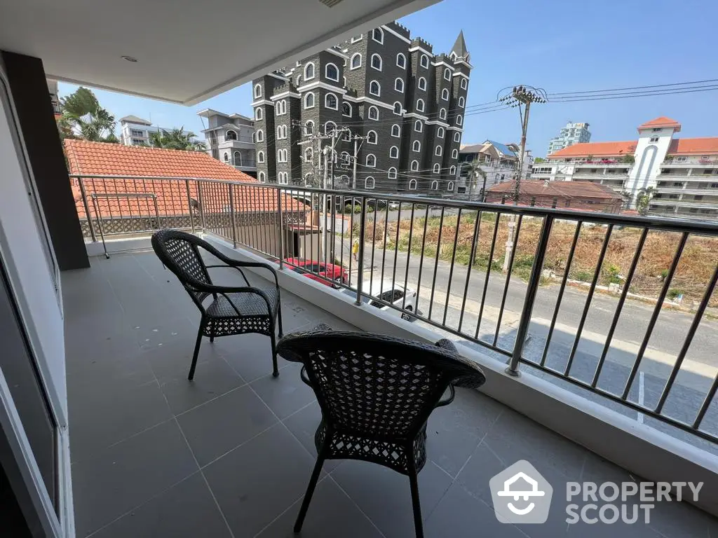 Spacious balcony with modern wicker chairs offering a view of an urban landscape, perfect for outdoor relaxation and entertainment.