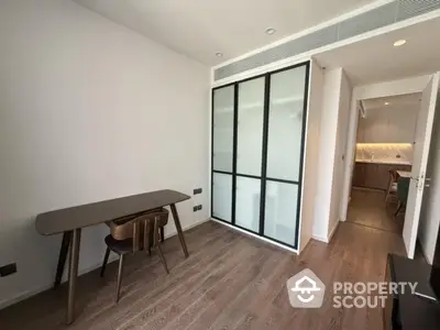 Modern study room with sleek wooden desk and chairs, featuring sliding glass doors and elegant flooring.