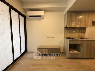 Modern apartment interior with sleek kitchen and air conditioning, featuring wooden cabinetry and flooring.