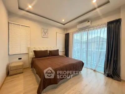 Spacious bedroom with modern decor and large windows offering natural light.