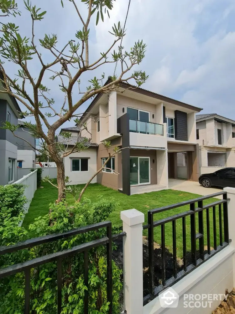 Modern two-story house with lush green lawn and sleek balcony design