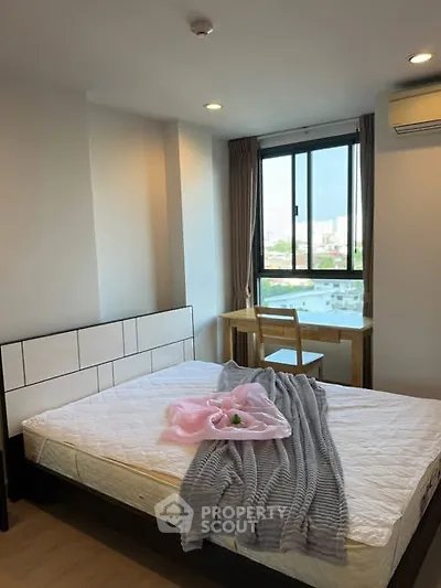 Cozy bedroom with large window and city view, featuring a stylish bed and modern decor.