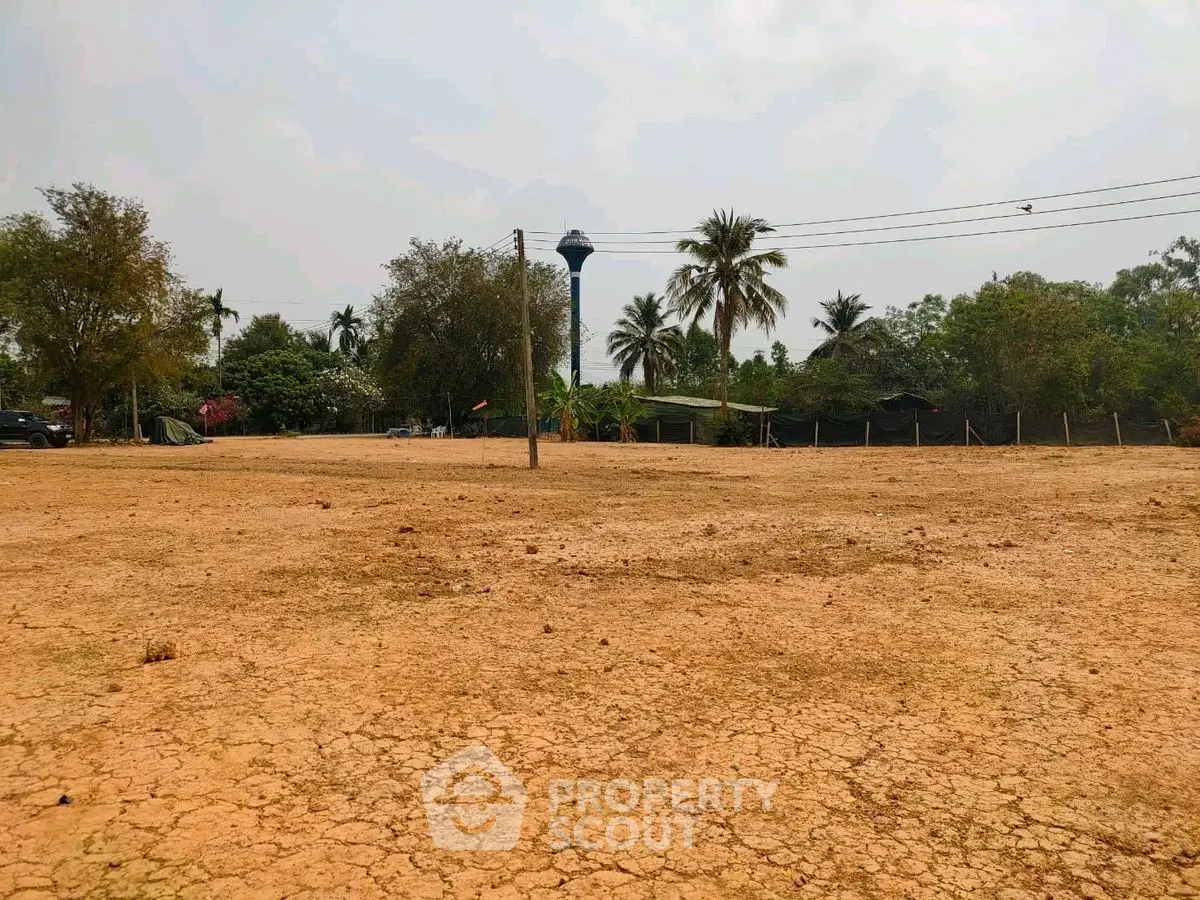 Expansive land plot with potential for development, surrounded by lush greenery and palm trees.