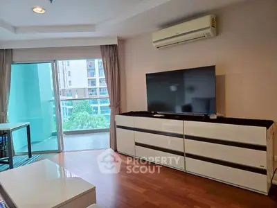 Modern living room with large TV and balcony view in urban apartment