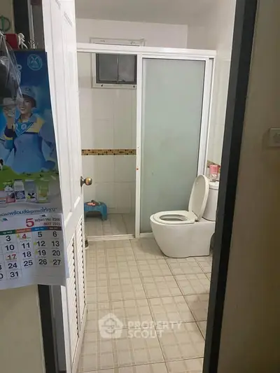 Cozy bathroom with sliding glass shower door and tiled flooring.