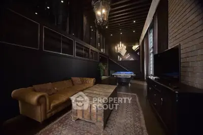 Luxurious living room with high ceilings, elegant chandelier, and pool table.