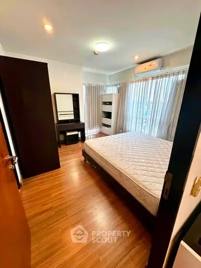Spacious bedroom with wooden flooring and large windows in modern apartment