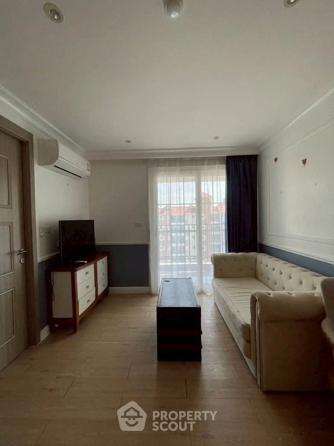 Cozy living room with natural light, modern furniture, and balcony access.