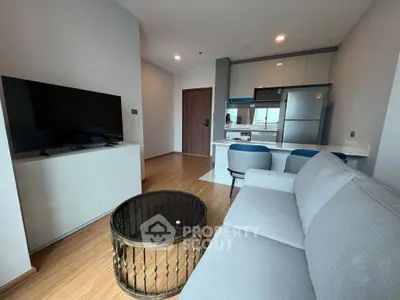 Modern open-plan living room with sleek kitchen and stylish furnishings in a contemporary apartment.