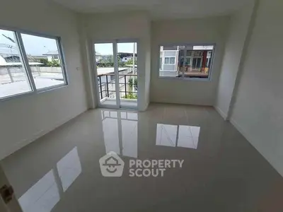 Spacious empty room with glossy tiled floor and large windows for natural light.