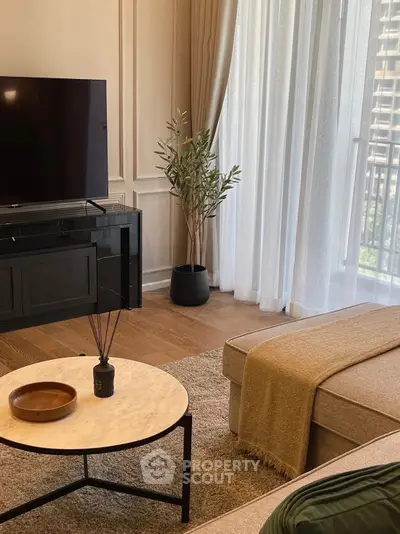 Elegant living room with modern decor, large TV, and natural light from balcony window.