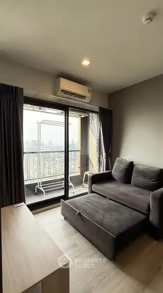 Modern living room with balcony and city view, featuring sleek furniture and air conditioning.