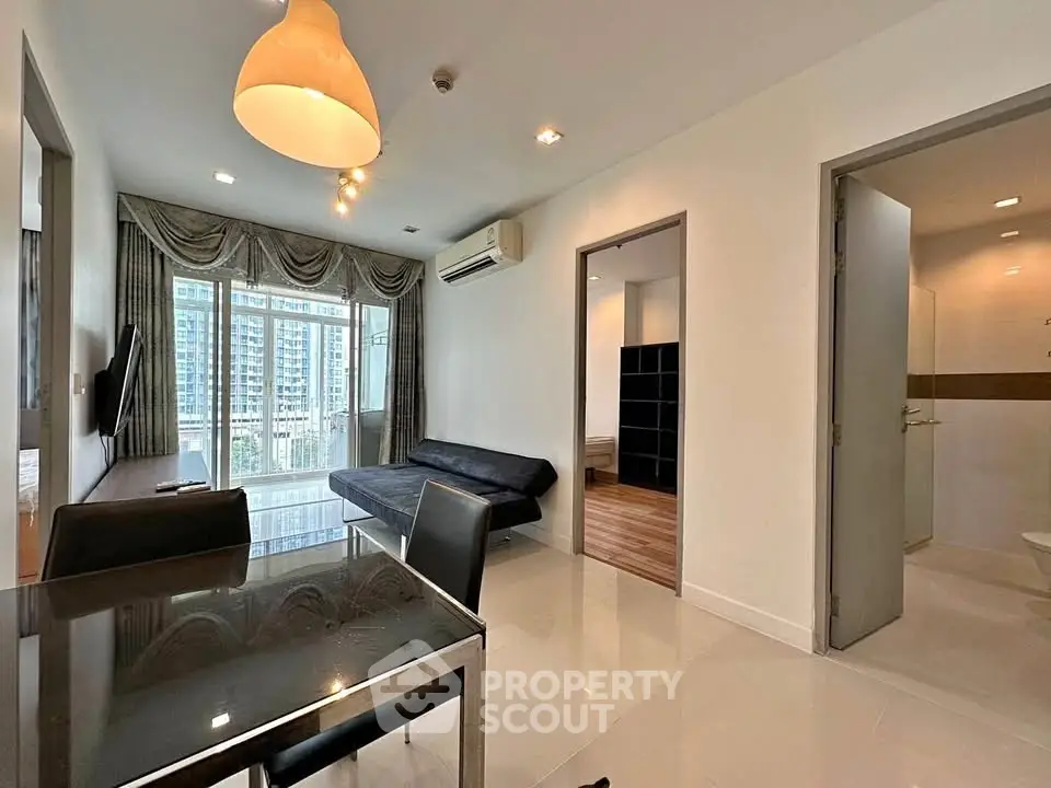 Modern living room with dining area and city view, featuring sleek furniture and ample natural light.