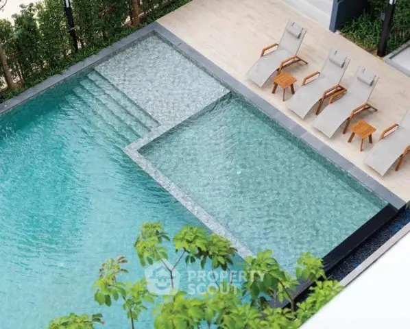 Luxurious outdoor pool area with sun loungers and lush greenery, perfect for relaxation and leisure.
