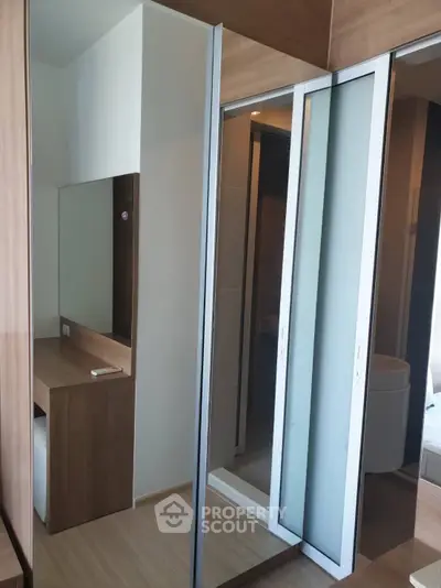 Modern bedroom with mirrored sliding closet doors and wooden vanity desk.