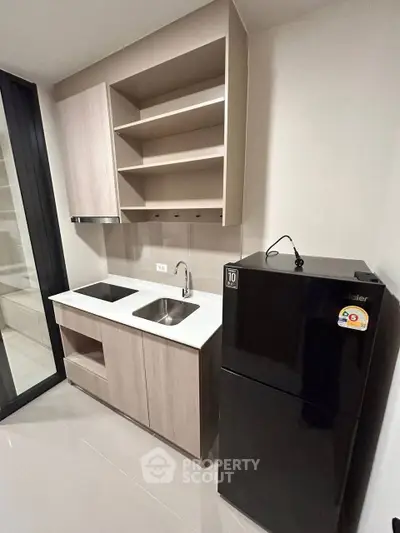 Modern compact kitchen with sleek cabinetry and black fridge