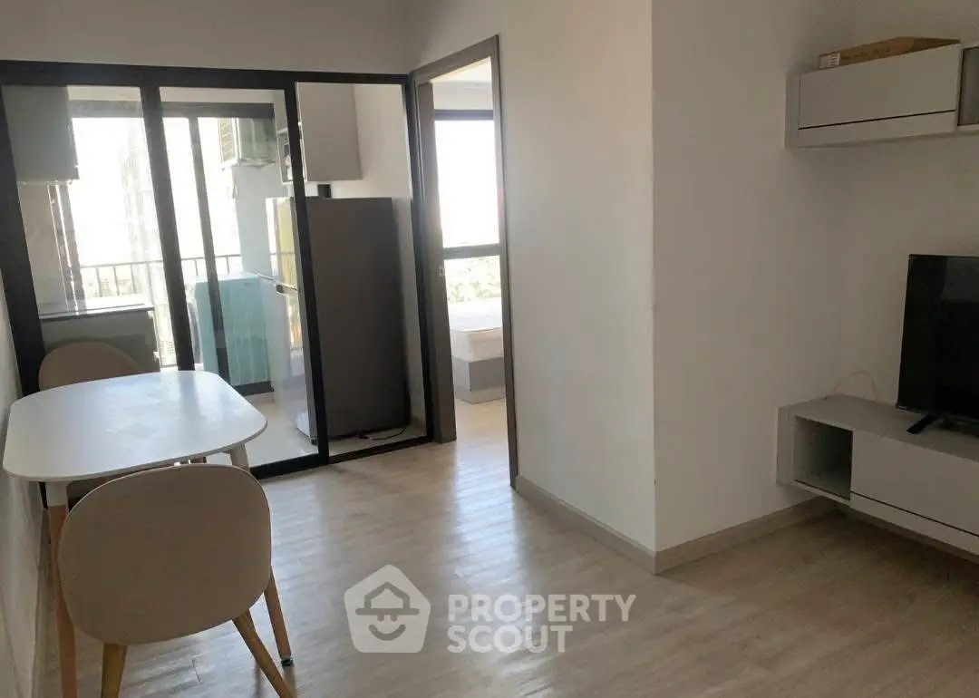 Modern apartment interior with dining area and TV, featuring sleek design and natural light.