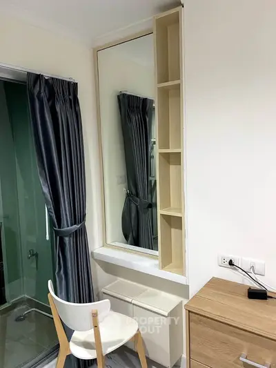 Modern bedroom corner with stylish mirror, sleek chair, and elegant curtains, perfect for a cozy living space.