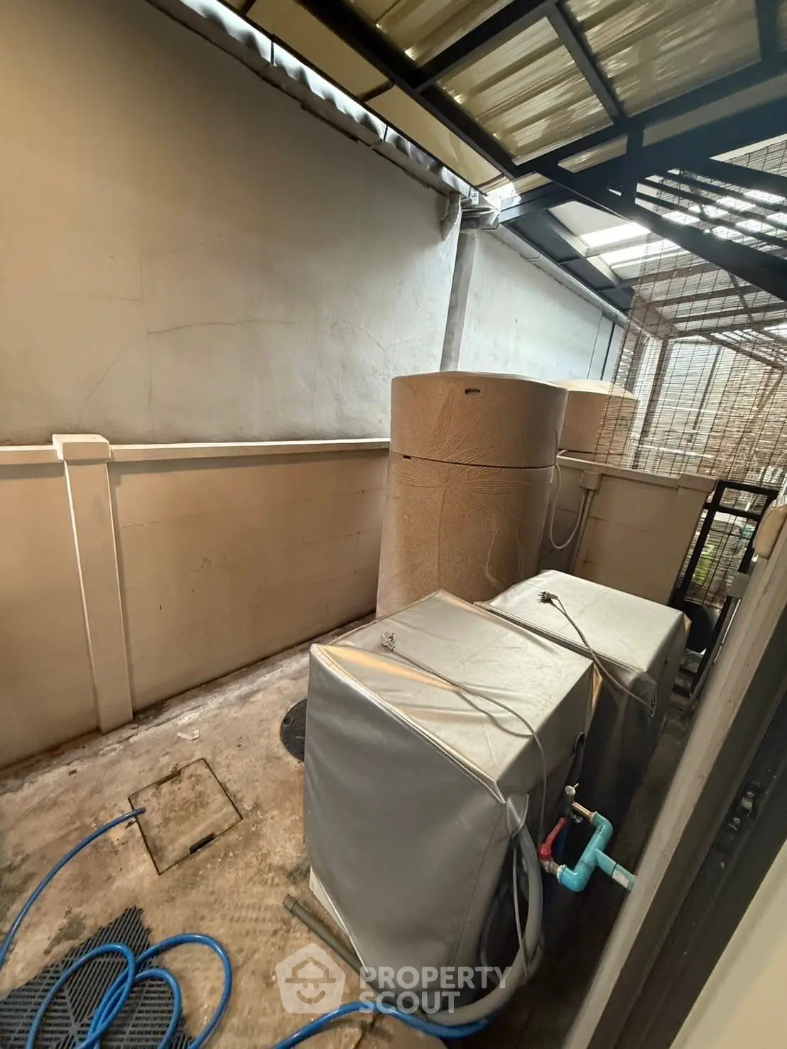 Outdoor utility area with water tanks and covered equipment, ideal for storage or maintenance.